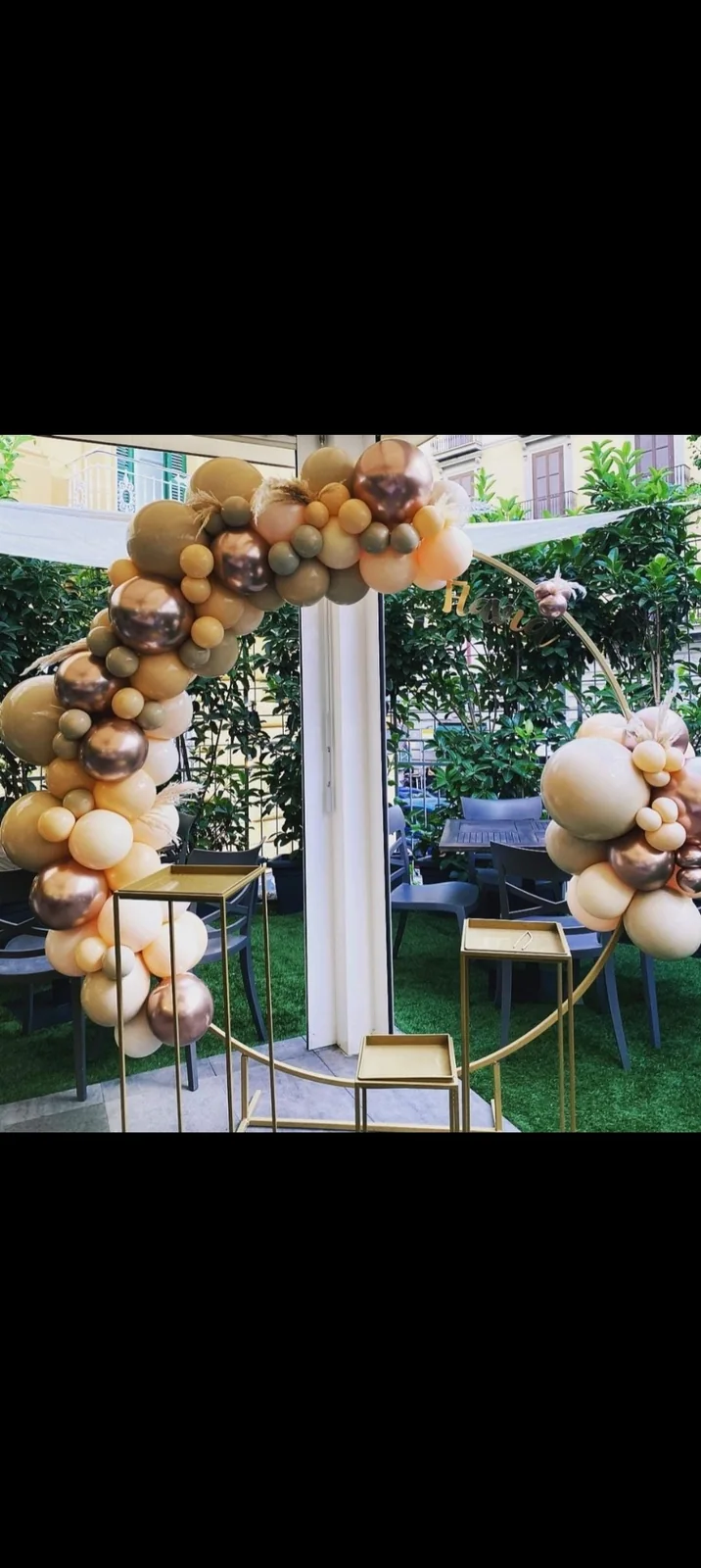 Arco di palloncini oro, avorio e marroni per un allestimento esterno.
