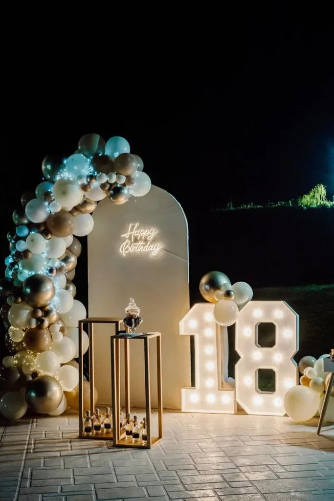 Allestimento serale per diciottesimo con numero luminoso e palloncini avorio e oro.