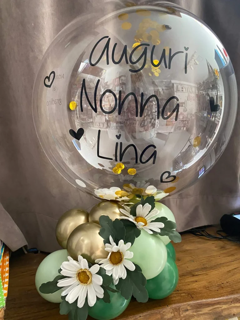Bolla personalizzata su base di palloncini verdi e oro, decorata con margherite bianche.
