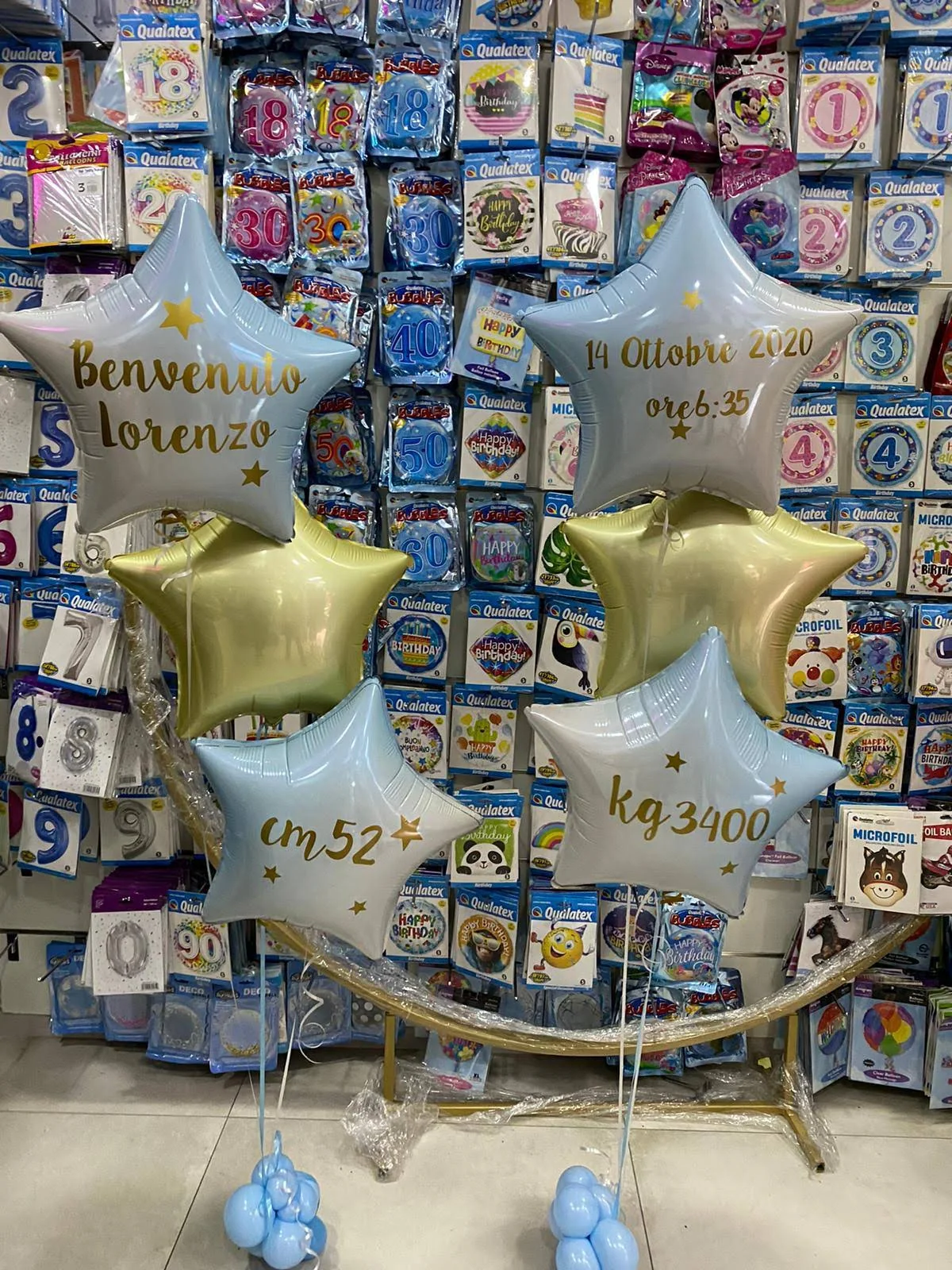 Composizione per una nascita con stelle personalizzate e palloncini azzurri e bianchi.
