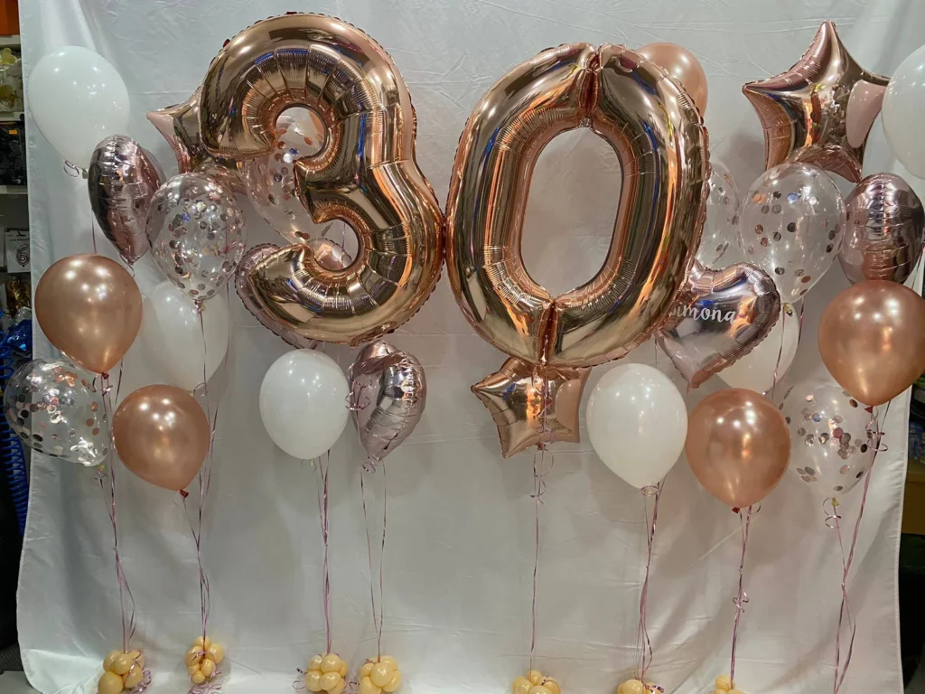 Bouquet con numero 30 rose gold, bolle trasparenti, stelle e palloncini bianchi.