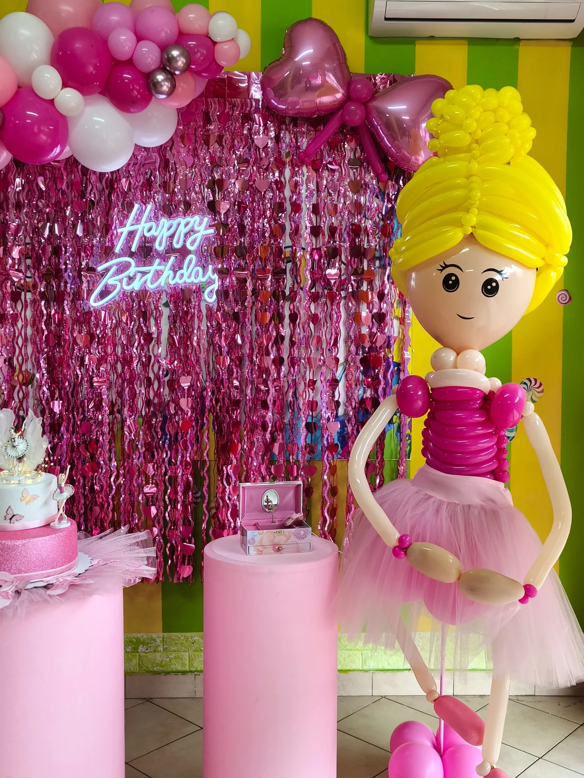 Allestimento per compleanno con fondale fucsia, palloncini rosa e scultura decorativa.