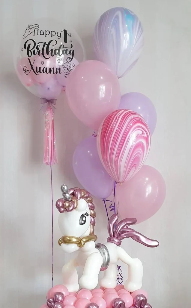 Composizione regalo con unicorno, palloncini rosa e bolla personalizzata.