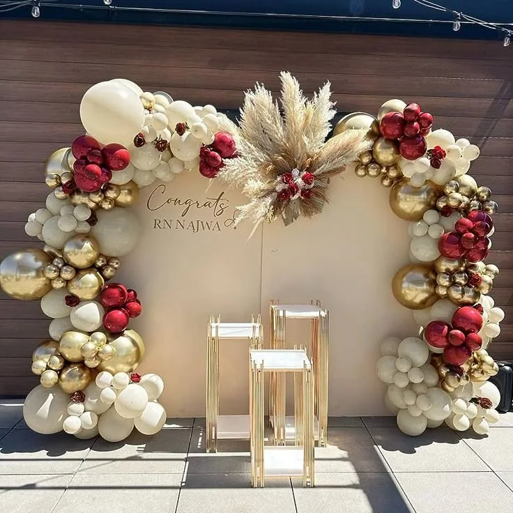 Allestimento per cresima con fondale chiaro e palloncini bordeaux, avorio e oro.