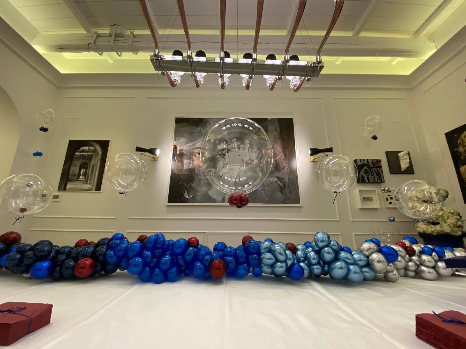 Decorazione di una sala con una lunga composizione di palloncini blu e azzurri e una sfera trasparente.