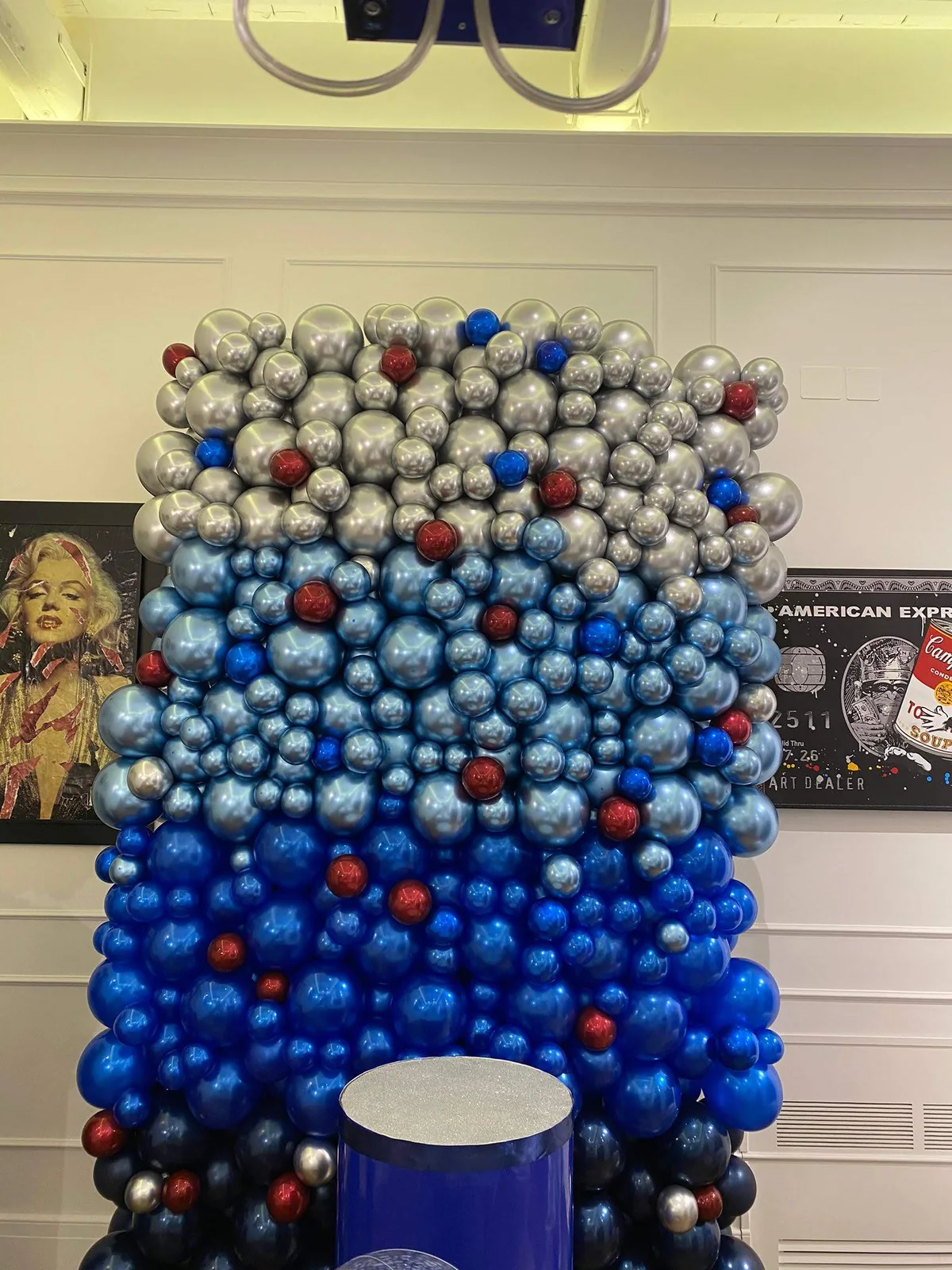 Parete scenografica con palloncini blu, azzurri, argento e dettagli rossi.