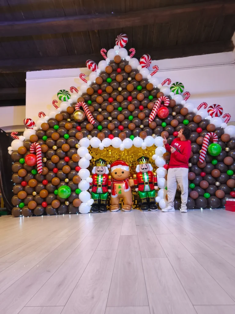 Grande scenografia natalizia di palloncini con casa di pan di zenzero, bastoncini e personaggi.