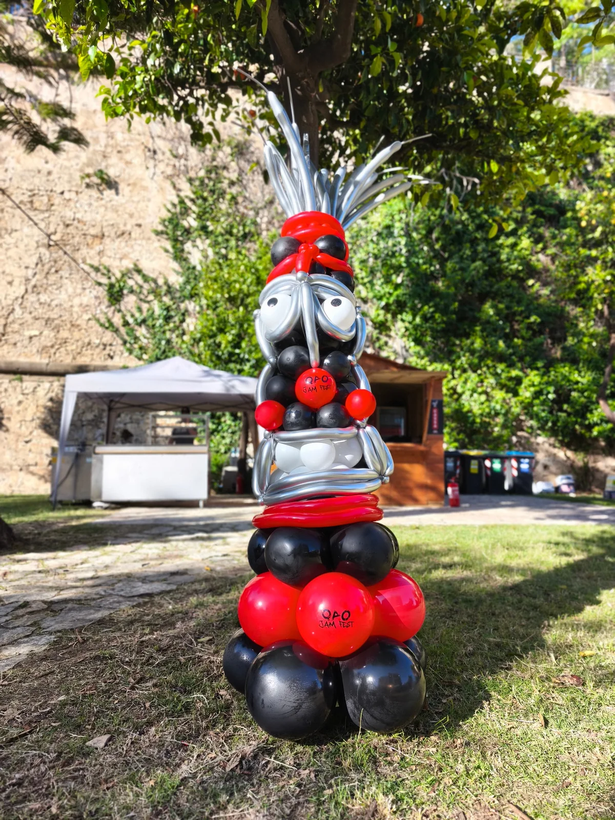 Scultura di palloncini rossi, neri e grigi a forma di moto con personaggio.